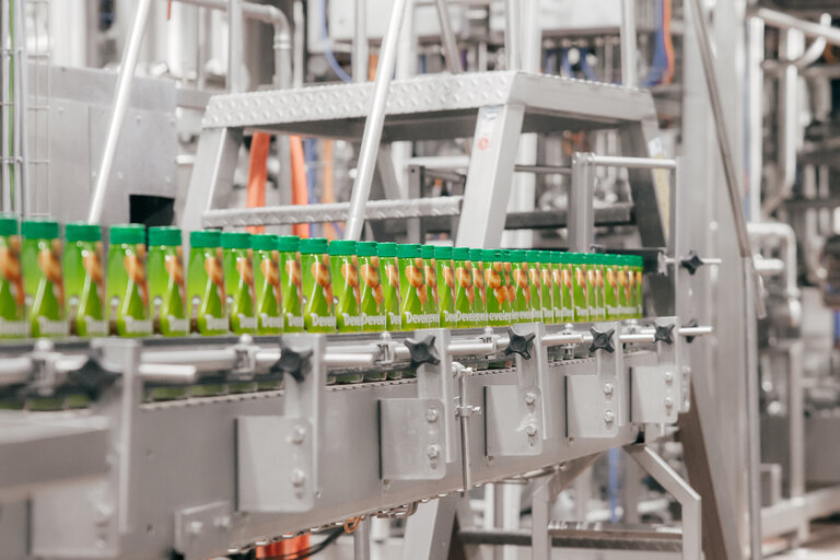 Gefüllte Develey Saucenflaschen laufen auf einem Förderband durch eine industrielle Abfüll- und Produktionsanlage.